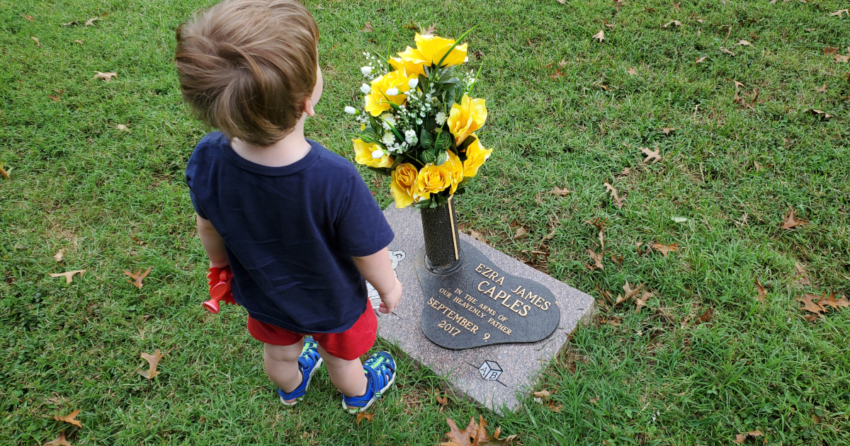 Ezra's 3-year old brother standing beside his grave marker