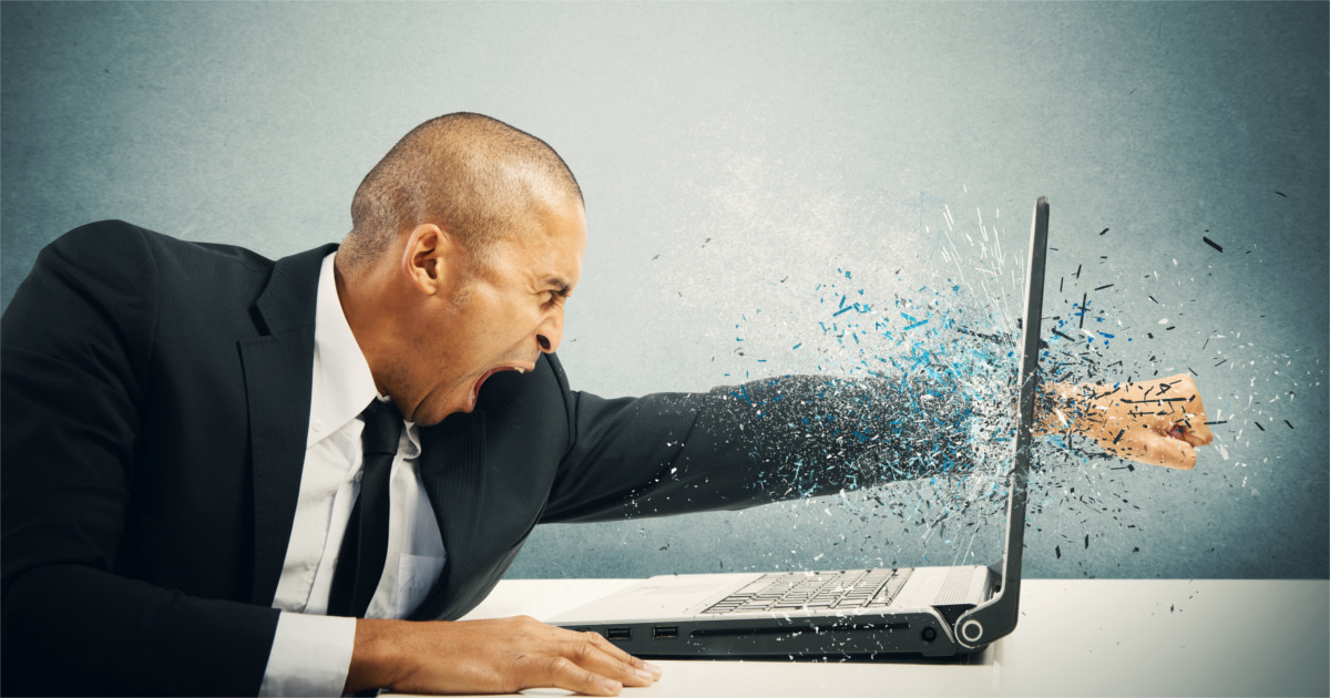Angry man punching through a laptop screen