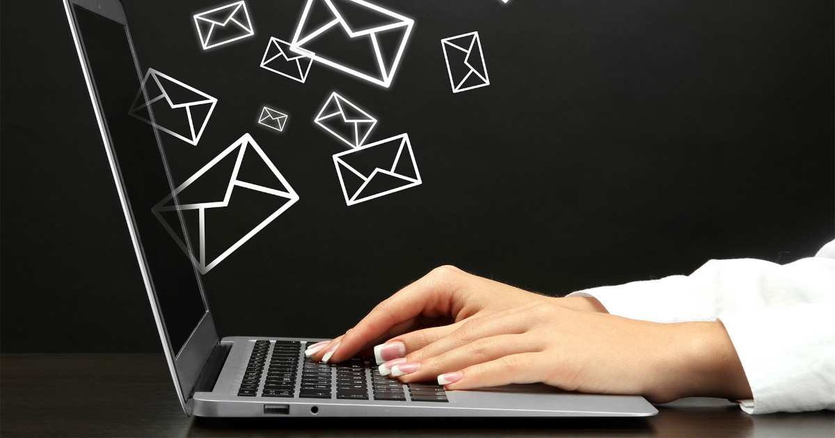 A woman typing on a laptop, with abstract emails flying out