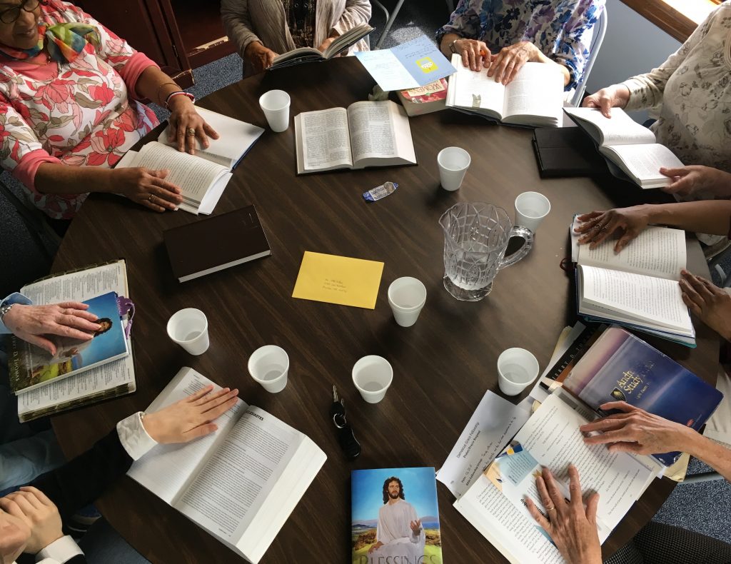 A group of people seated at a table studying the Bible together